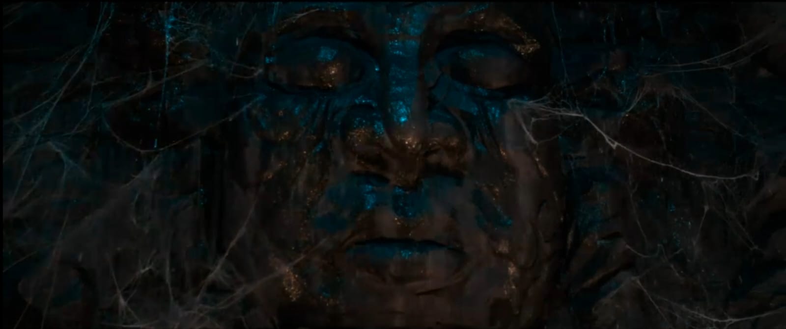 Giant ancient face with teal-gold shimmer